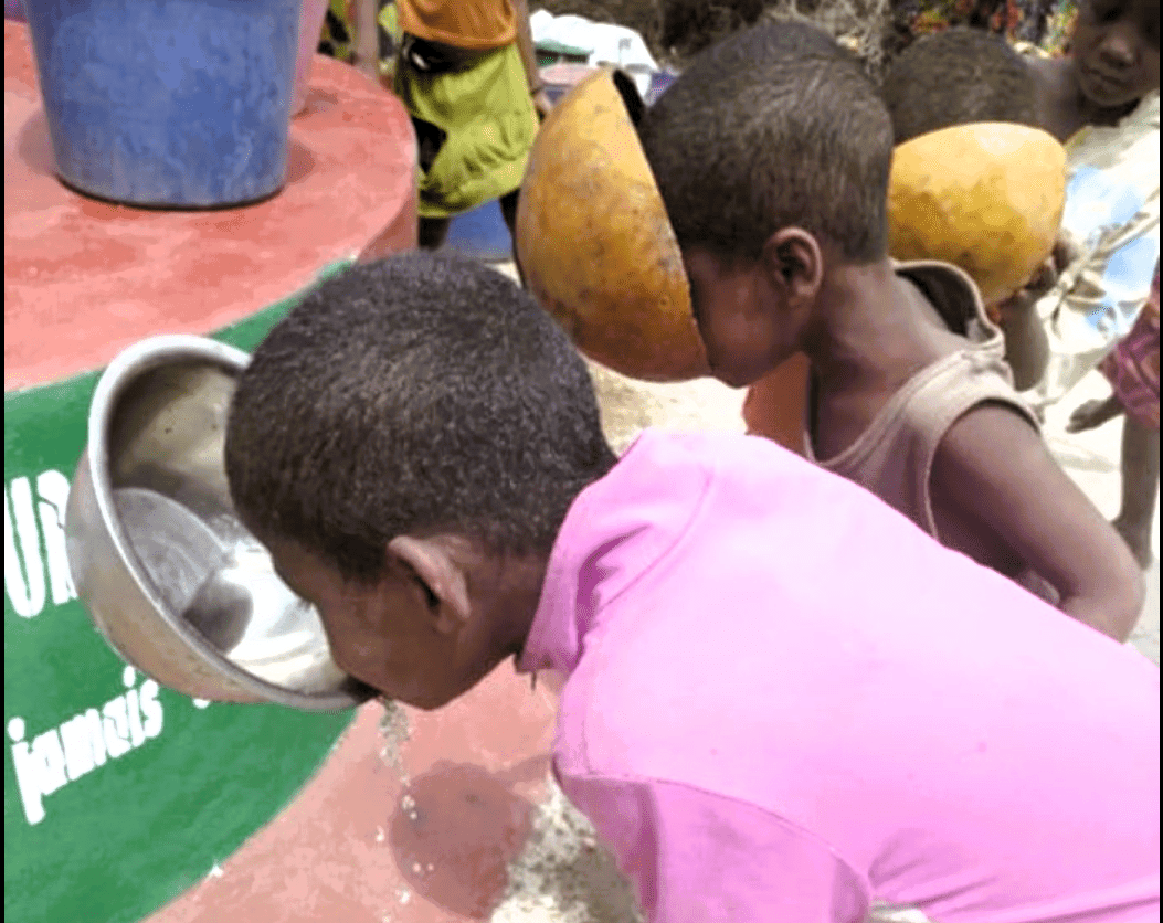 Thirsty children taking their first drink from the new well in Madagascar